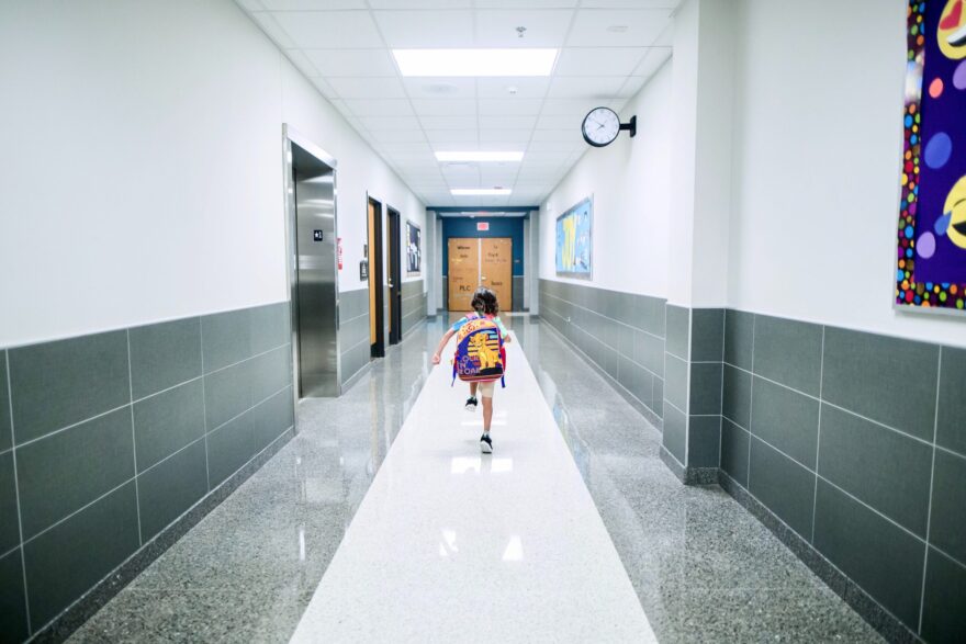 Un niño camina por un pasillo de un colegio.